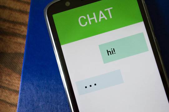 smartphone displaying generic application with message app in screen, on table with dramatic lighting