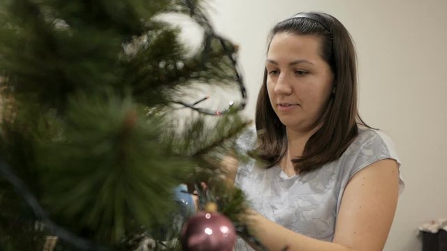 Happy family decorating a Christmas tree with boubles in the living-room
