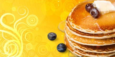 Pancakes with currants and honey on a yellow background