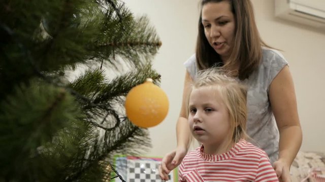 Happy family decorating a Christmas tree with boubles in the living-room