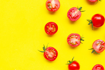 Fresh cherry tomatoes, whole and half cut isolated on yellow background.