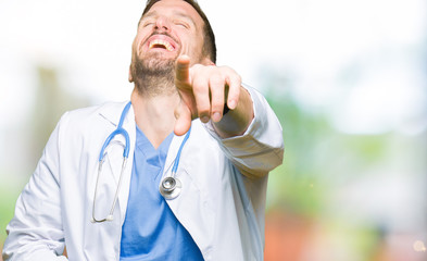 Handsome doctor man wearing medical uniform over isolated background Laughing of you, pointing to the camera with finger hand over chest, shame expression