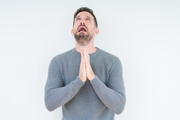 Young handsome man wearing casual sweater over isolated background begging and praying with hands...