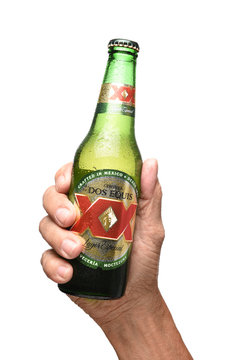 IRVINE, CALIFORNIA - JULY 25, 2019: A hand holding a bottle of Dos Equis Lager over white.