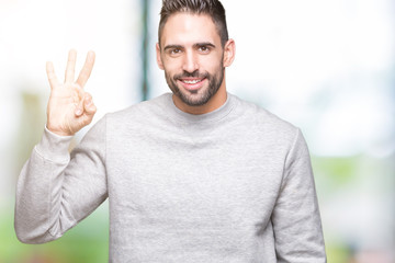 Young handsome man wearing sweatshirt over isolated background showing and pointing up with fingers number three while smiling confident and happy.