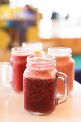 Assortment of seasonal colorful smoothies in jars on a wooden table
