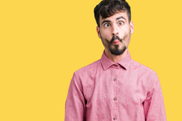 Obraz premium Young handsome man wearing pink shirt over isolated background making fish face with lips, crazy and comical gesture. Funny expression.