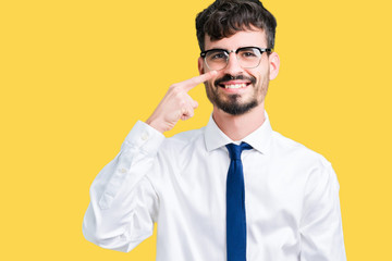 Young handsome business man wearing glasses over isolated background Pointing with hand finger to face and nose, smiling cheerful