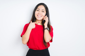 Young brunette woman talking on smartphone over isolated background very happy pointing with hand and finger
