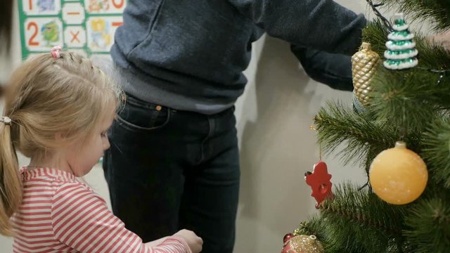 Happy family decorating a Christmas tree with boubles in the living-room