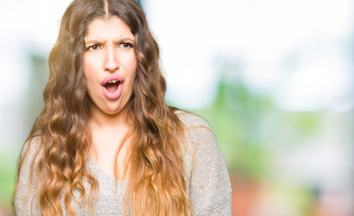Fototapeta premium Young beautiful woman wearing winter dress In shock face, looking skeptical and sarcastic, surprised with open mouth
