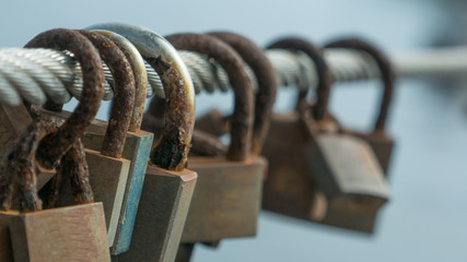 Row of corroded, rusty love locks / padlocks attached to bridge in Portugal. Close up / macro with shallow depth of field.