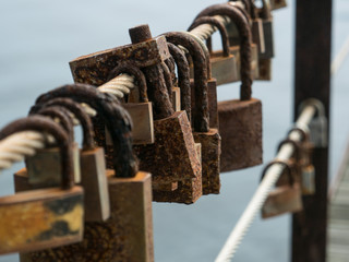 Rusted, corroded love locks / padlocks attached to a bridge. Shallow depth of field