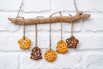 Gingerbread cookies hanging on a rope over a white brick wall. Christmas decoration.