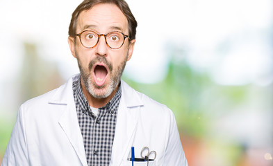 Middle age doctor men wearing medical coat afraid and shocked with surprise expression, fear and excited face.