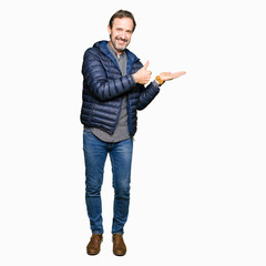 Naklejka premium Middle age handsome man wearing winter coat Showing palm hand and doing ok gesture with thumbs up, smiling happy and cheerful