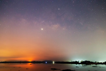 Naklejka na ściany i meble Landscape of the milky way galaxy over the river with sunrise at rural Thailand. Star light on the sky with tree at Sisaket province ,Thailand.
