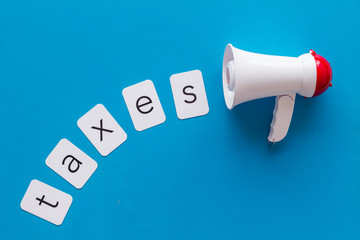 Taxes announcement with megaphone and text on blue background top view