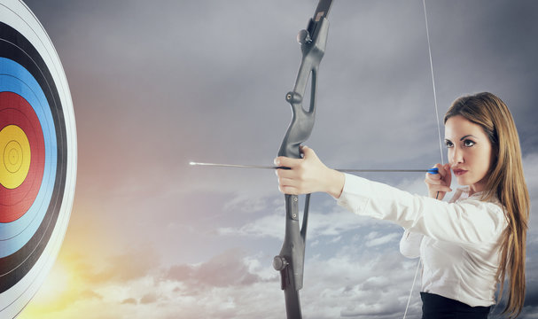 Businesswoman with bow and arrow pointing the center of the target.