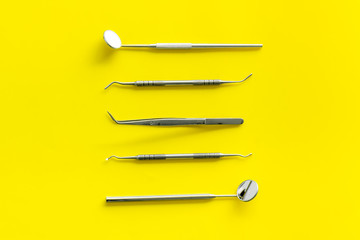 Dentist work desk with tools for teeth on yellow background top view