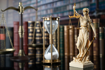 The law concept background.  White statue of Themis, gavel, legal books, scale and the hourglas on...