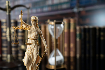 The law concept background.  White statue of Themis and legal books on the table in the old court library.