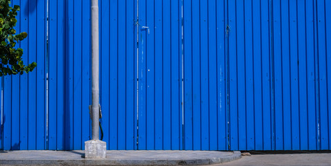 blue steel sheet wall and tree on the street