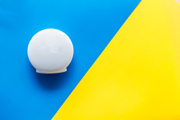 Portable wireless speakers as gadgets for listen to the music on blue and yellow background top view copy space