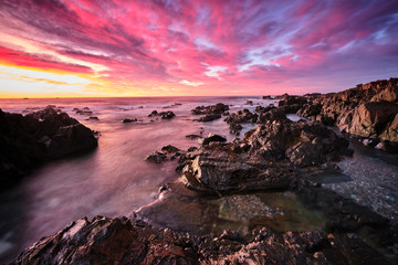 Red sky sunrise with water motion and flow over rocks