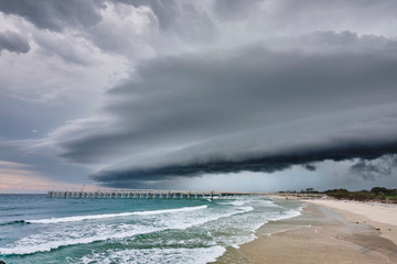 Large shelf cloud storm coming over sand pumping jetty during storm season australia