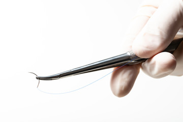 Doctor holding needle holder on white background. Suture thread. Nylon surgical thread.