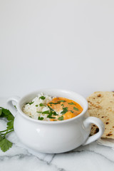 Indian butter chicken with rice, cilantro, and naan, copy space, white background