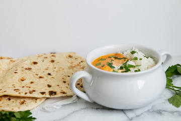Indian butter chicken with rice, cilantro, and naan, copy space, white background