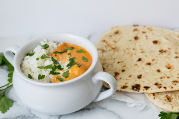 Indian butter chicken with rice, cilantro, and naan, copy space, white background