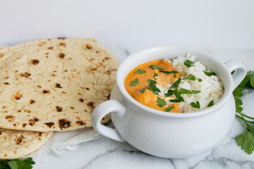 Indian butter chicken with rice, cilantro, and naan, copy space, white background