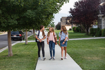 Group of cute young female friends and students talking together as they walk home school for the day
