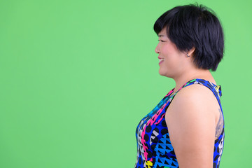 Closeup profile view of young happy overweight Asian woman smiling ready to party