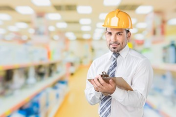 Engineer taking a note. Focused man in white hardhat holding a clipboard and writing.