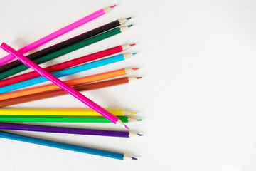 Many colored pencils lie on a white background. Copy spase. The concept of back to school, the educational process, study at school, drawing