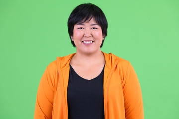 Face of young happy overweight Asian woman smiling ready for gym