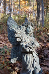 Weathered stone fairy sculpture in an autumn forest