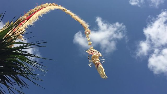 Slow Motion Traditional Bali Penjor bamboo pole with decoration on village street in front of Balinese people houses and temples on Galungan Kuningan holidays. Copy space