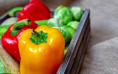 Various non-toxic fresh vegetables are placed in a wooden box placed on a mat. Many vegetables are purple and green sprouts, red pepper Yellow and green, Corn and others