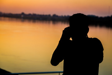 Siluate of man taking pictures before sunset