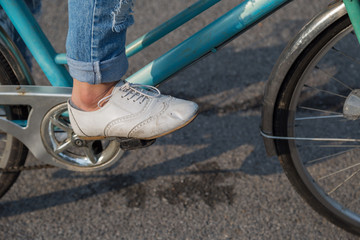 Obraz premium Female wearing jeans and wearing white shoes rides bicycle