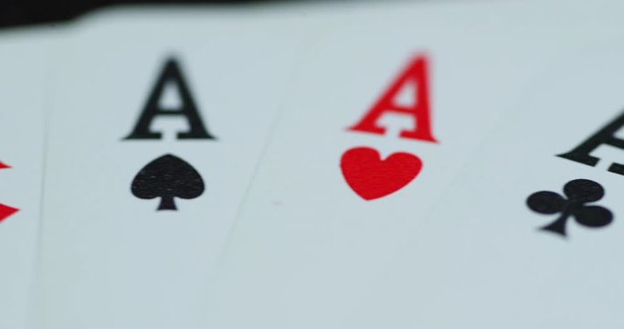 Macro detail shot of top of playing cards with all four aces hearths diamonds space cross lying on an elephant while moving as the cards slowly expose from the side.