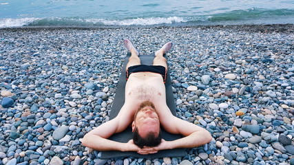 a man sunbathes on a pebble beach near the warm sea, rest after a hard working year