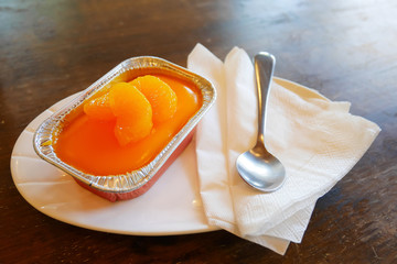 Orange cake on a white dish with spoon and tissue paper at the coffee shop.
