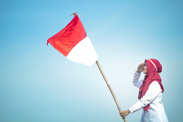 Asian Hijab Holding and respect Indonesian flag with clear blue skyand Plaosan Temple background, Indonesia independence day
