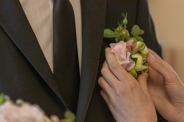 bride ties a boutonniere to the groom